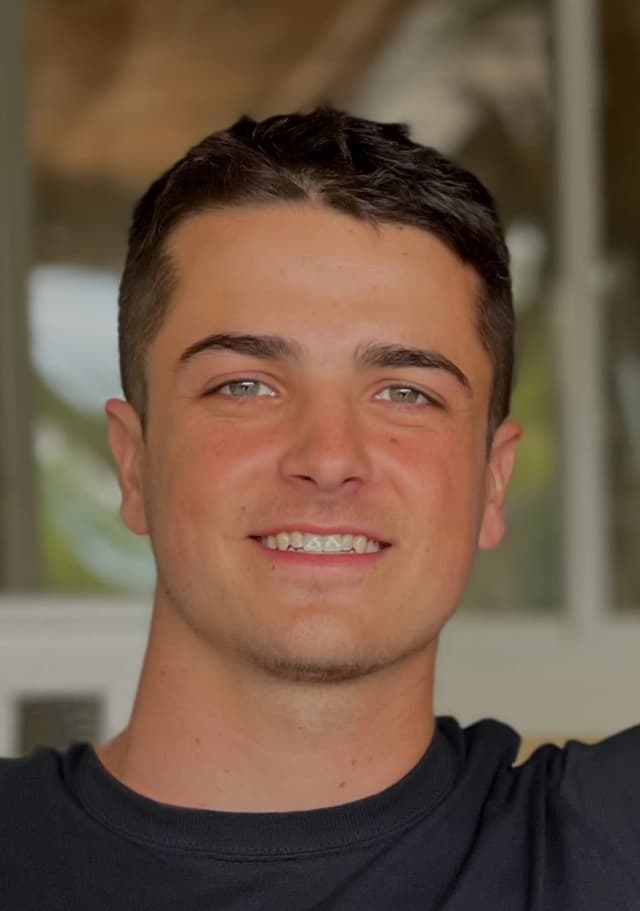 A headshot of Coach Brady Moore. A young man with caucasian features and short brown hair smiles at the camera.