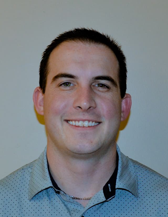 A headshot of Coach Matt Palmieri. A young man with caucasian features and short brown hair smiles at the camera.